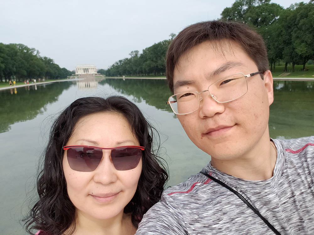 Woman and man pose in front of the reflection pool with the Lincoln Memorial in the background